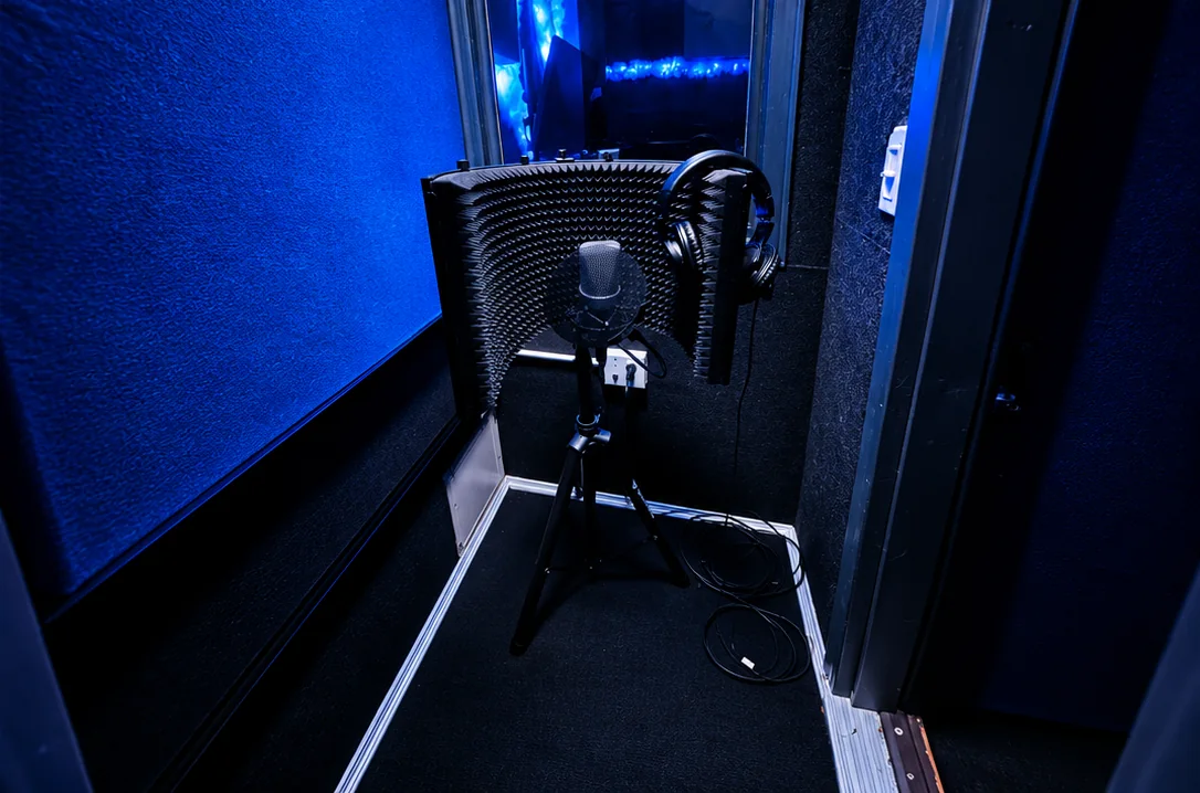 The private vocal booth under blue light, looking back toward the control room